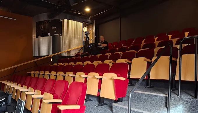 Zeo aan het werk bij de geluidstechniek in een theaterzaal met rode stoelen